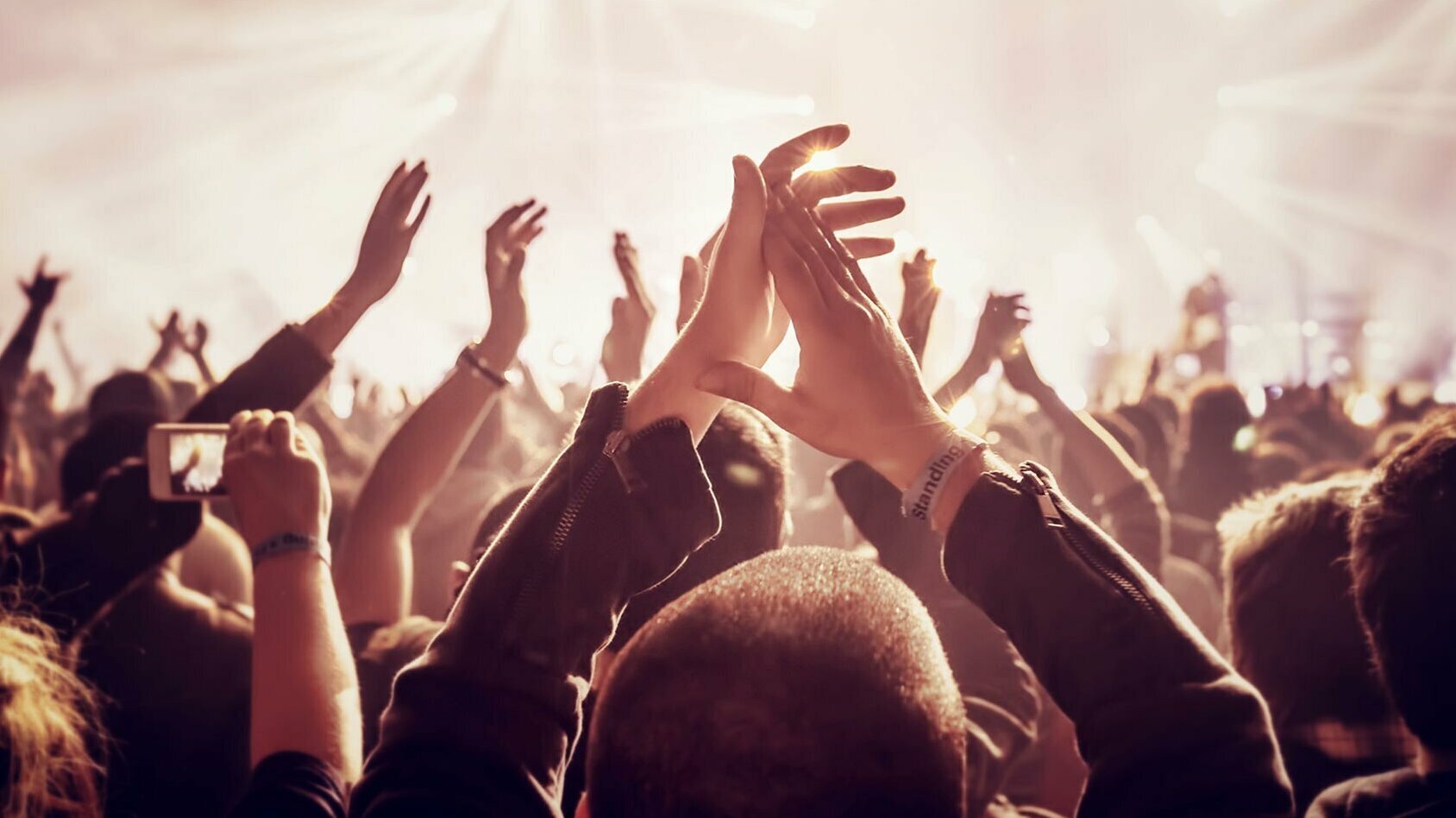 eine Menschenmenge, die die Hände in die Luft streckt und applaudiert